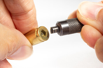 Reloading/handloading - closeup of 9mm Brass/casing primer pocket being cleaned and prepared for...