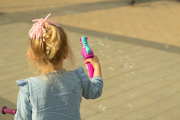 The child lets soap bubbles. A girl plays with a toy on the street.