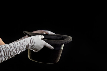 Hand gestures. illusionist holds a hat in his hands and shows magic and tricks. Black background