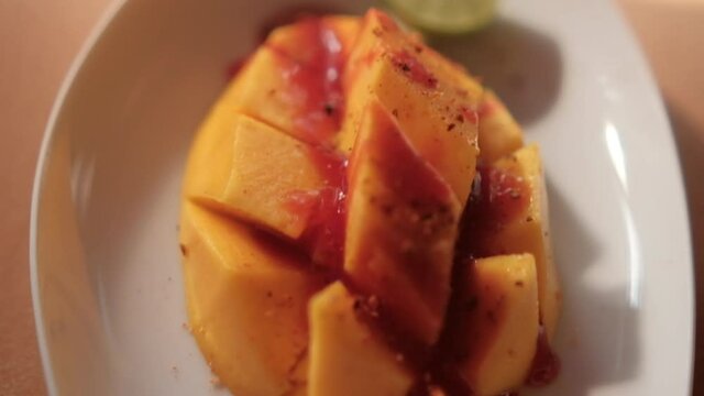 Plate of chopped mango with Mexican chamoy sauce and blurry background