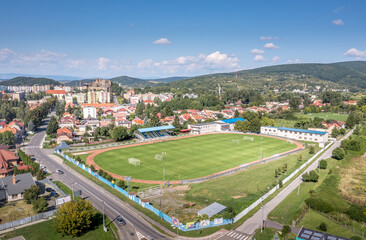 Fototapeta na wymiar old versus new in Fialkovo Slovakia, modern residence building, soccer field with medieval hilltop castle ruin in the background