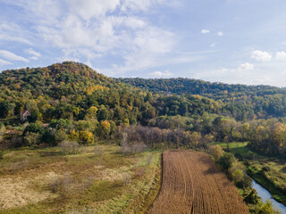 aerial view of farm fielding bluffs in autumn with natural colors and blue sky; harvested corn field; open environment