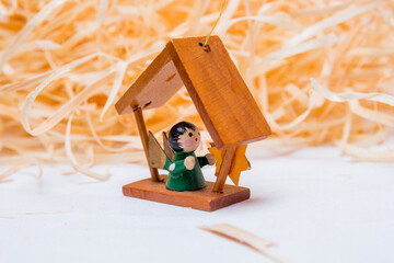 Fototapeta na wymiar little wooden angel on a white background with straw in the background.