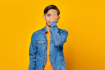 handsome young man and stylish haircut looking at camera, covering one eye with palm as if his eye is being tested during vision check