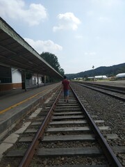 Fototapeta na wymiar Man walking down train tracks perspective shot in Iryeong Station in South Korea
