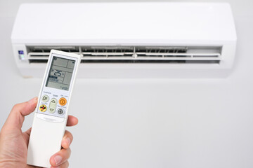 Fototapeta premium Man's hand using remote control open The air conditioner is cooled to 25 degrees Celsius in his bedroom. Health concepts and energy savings