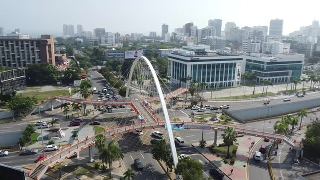toma de drone con movimiento 180 grados de puente peatonal con vista de edificios al fondo, clima soleado en santo domingo 