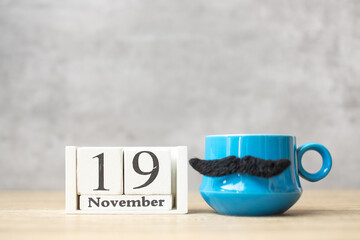 International Men day with November 19 calendar, Blue coffee cup or tea mug and Black mustache decor on table. Happy father day and celebration concept