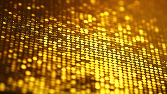 Abstract gold background. Sequin backdrop. Gold Metallic Glitter fabric surface. Holiday glitter background with blinking lights. Golden Fabric sequins. Rotating Holiday Fashion fabric glitter