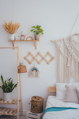 Home interior in a Scandinavian style. Bed, wooden shelf, wooden clothes rack, wicker basket. The concept of cleanliness and home comfort.