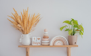 Obraz premium Wooden shelf with stylish children's wooden toys. Pyramid, rainbow and white wooden cubes with the inscription one day. Home comfort concept.