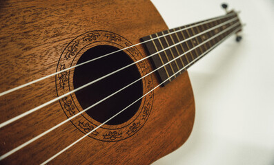 Obraz premium Close up of brown Ukulele on white background. Ukulele strings, saddle, soundhole, ukulele body, neck, fretboard.