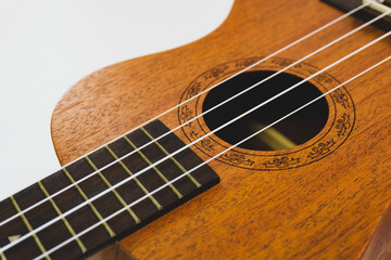Obraz premium Close up of brown Ukulele on white background. Ukulele strings, saddle, soundhole, ukulele body, neck, fretboard.