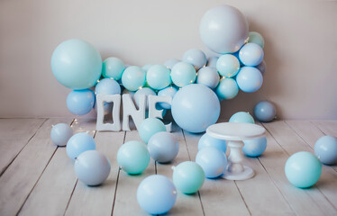 Card. Stylish photo zone in light colors with mint and blue balloons, one wooden inscription and a cake stand. Light background, white wood floor. Сake smash concept.