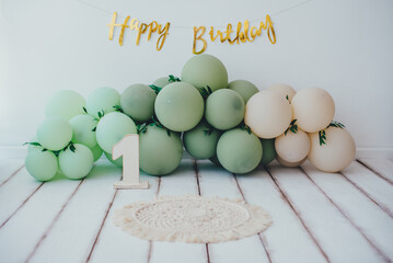 Card. Stylish photo zone in light colors with balloons and a wooden number one and the inscription Happy Birthday. Light background white wood floor. Сake smash concept.