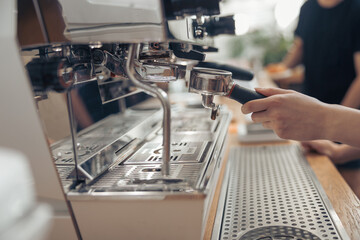 Female barista using professional coffee machine in cafe