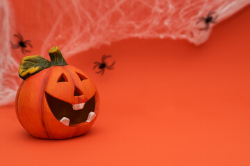 Halloween pumpkin with cobwebs and black spiders in the background on an orange background, place for text.
