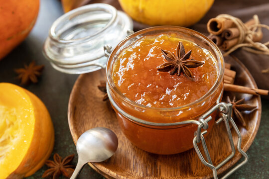 Homemade preserved, delicious sweet spicy sauce close-up. Pumpkin confiture, jam, chutney sauce with spices on stone table.