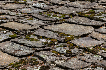 Old stone tiles for roof covered with moss