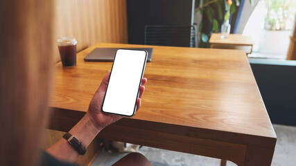 Naklejka premium Mockup image of a woman holding mobile phone with blank white desktop screen