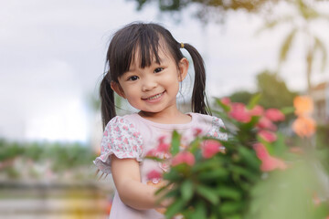 Portrait​ image of​ 3-4 years old​ childhood​ child. Face of smile and laugh Asian​ girl in head shot. Happy​ kid playing​ at the park playground. In summer or spring​ season.