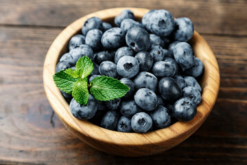 Freshly picked blueberries in wooden bowl on wooden background.  Concept of healthy and dieting eating.
