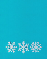 White tracing paper snowflakes on blue background, top view, flat lay, copy space. Handmade new year decoration