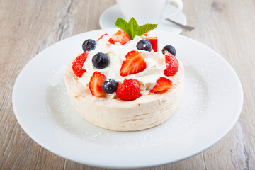 Pavlova dessert on a white plate with a cup