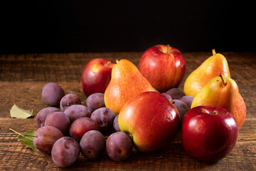 Fresh plums and pears lying on a wooden table.Fresh, juicy fruits lying on a wooden table.