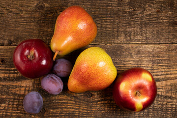 Fresh fruit lying on a wooden table.Apples, pears, fresh leaves and plums on a wooden background.