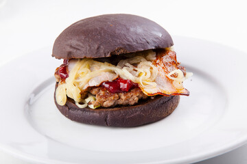black burger with bacon cutlet, fried onions and cherry sauce