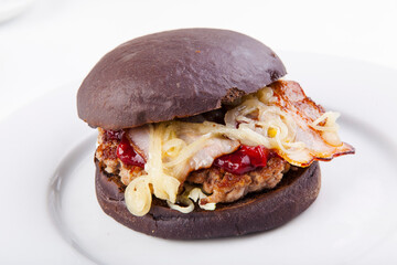 black burger with bacon cutlet, fried onions and cherry sauce