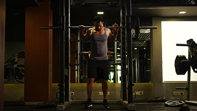professional athlete bodybuilder working out in the indoor gym. weight lifting and lower body muscle strength building workout. man doing squat, leg exercise for fitness. hamstring thighs training.