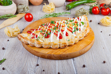 pizza calzone with red and white sauce on a wooden board