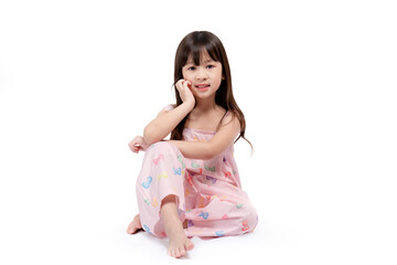 Beautiful Asian girl smiling brightly in a pink dress sits relaxing posting for fashion shoot on white background. Happy, healthy, bright cute boy