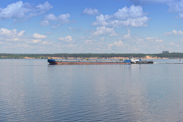 A cargo river barge sails along the Volga River on a sunny summer day