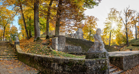 Park stairs with stone statues. Medieval castle in autumn. Autumn landscape of fortress with stone towers surrounded by autumn forest. Cesis castle in Latvia. - obrazy, fototapety, plakaty
