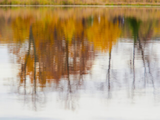 Autumn color is reflected in the still water of the lake