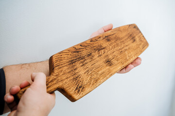 cutting board for cooking in the kitchen. a wooden board in the hands of a man. kitchenware. handmade carpenr's item.