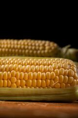 Fresh corn cobs on a black background