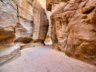 Picture with al-Siq, the natural passage through red rock walls which is main entrance to the ancient Nabatean city of Petra in southern Jordan.