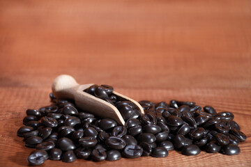 Wooden spoon in coffee beans on the background of natural wood texture with text space: making high-quality coffee in the morning, morning drink for energy