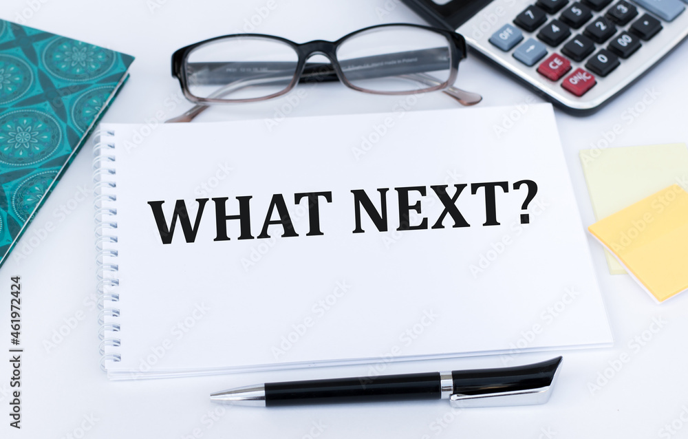Poster notebook with the text what's next on a white background next to glasses, a pen, a calculator