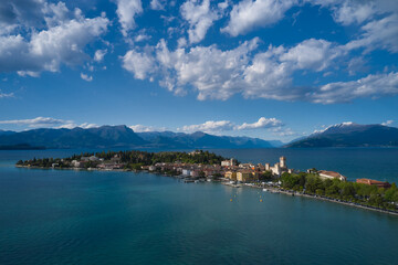 Aerial view of the island of Sirmione. Sirmione, Lake Garda, Italy. Panorama of Lake Garda. Peninsula on a mountain lake in the background of the alps. Castle on the water in Italy.