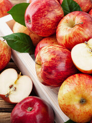 Close up of fresh organic apples and green leaves in wooden box. Vertical. New Zealand gala variety.
