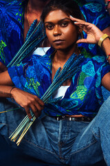 portrait of dark skinned Indian woman from Malaysia against a dark blue background with blue flowers
