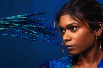 portrait of dark skinned Indian woman from Malaysia against a dark blue background with blue flowers