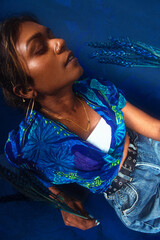 portrait of dark skinned Indian woman from Malaysia against a dark blue background with blue flowers