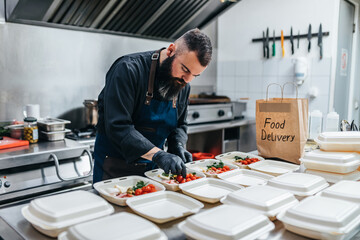 Food in disposable dishes ready for delivery. The chef prepares food in the restaurant and packs it...