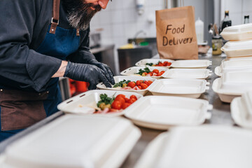 Food in disposable dishes ready for delivery. The chef prepares food in the restaurant and packs it...
